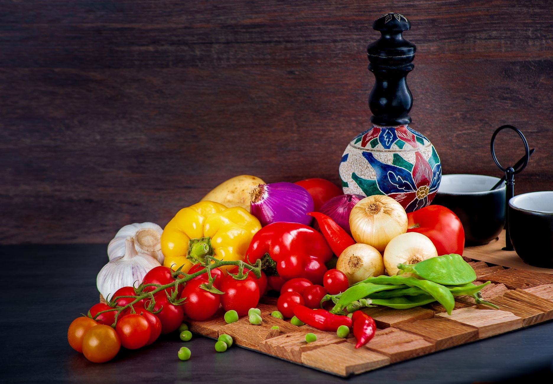 Colorful fresh vegetables including tomatoes, peppers, and onions on a wooden table